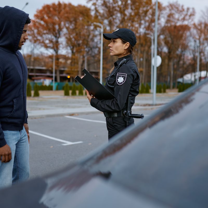 Police woman officer issuing fine ticket to offender. Female cop doing her job. Offense punishment