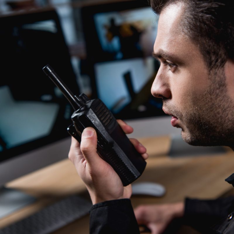 selective focus of guard holding walkie-talkie at workspace